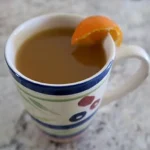 Hot Sweet Potato Apple Cider with an orange wedge in a mug