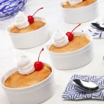 Sweet Potato Crème Brulee in white dishes topped with whipped cream and a cherry