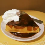 Sweet Potato Flan with Whipped Cream on a white plate